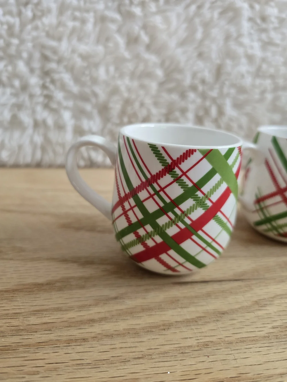 Crate & Barrel brand holiday mugs featuring a red and green plaid pattern